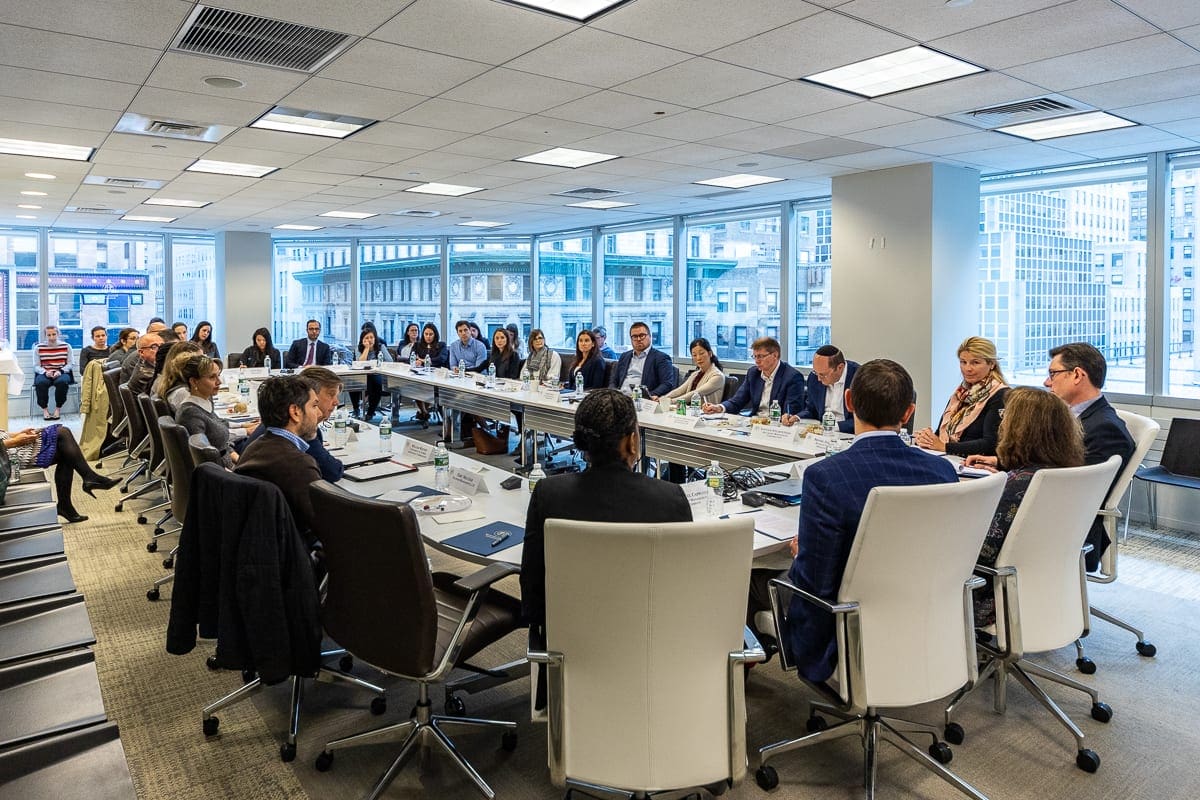 Men and women sit at a conference table discussing environmental, social and governance, or ESG, frameworks at an Remitop forum.